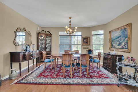 a dining room with wooden floor a chandelier fan a wooden table and chairs