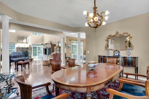 a dining room with wooden floor a chandelier a glass table and chairs