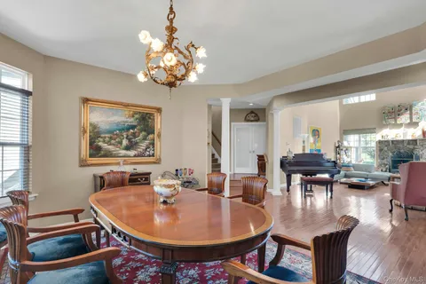 a dining room with wooden floor a chandelier a glass table and chairs