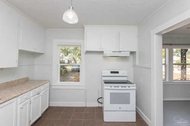 a kitchen with granite countertop a stove a sink and a refrigerator