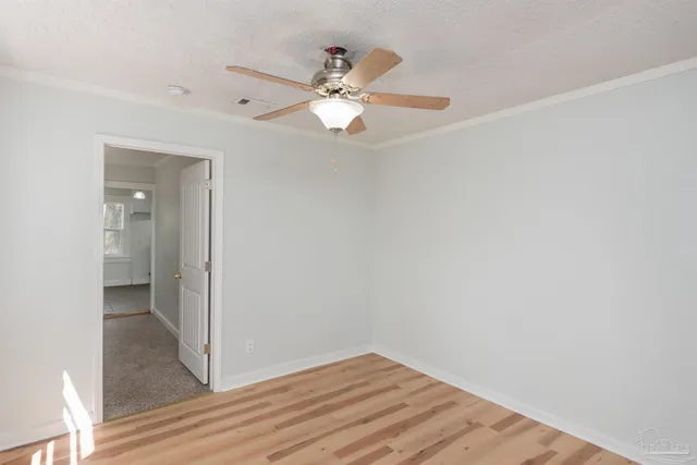 an empty room with wooden floor fan and windows