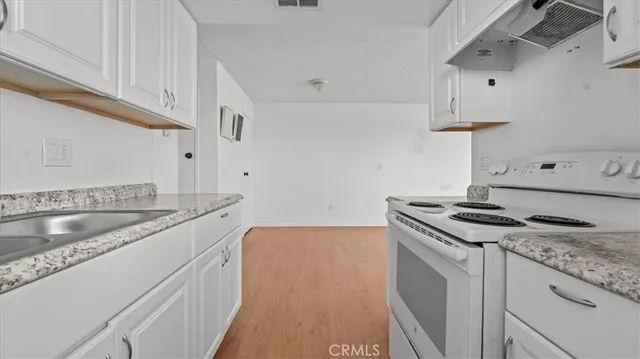 a kitchen with granite countertop a sink stove and cabinets