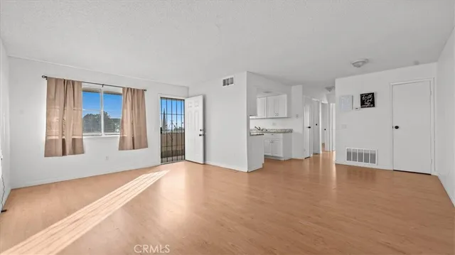 a view of an empty room with a window and wooden floor