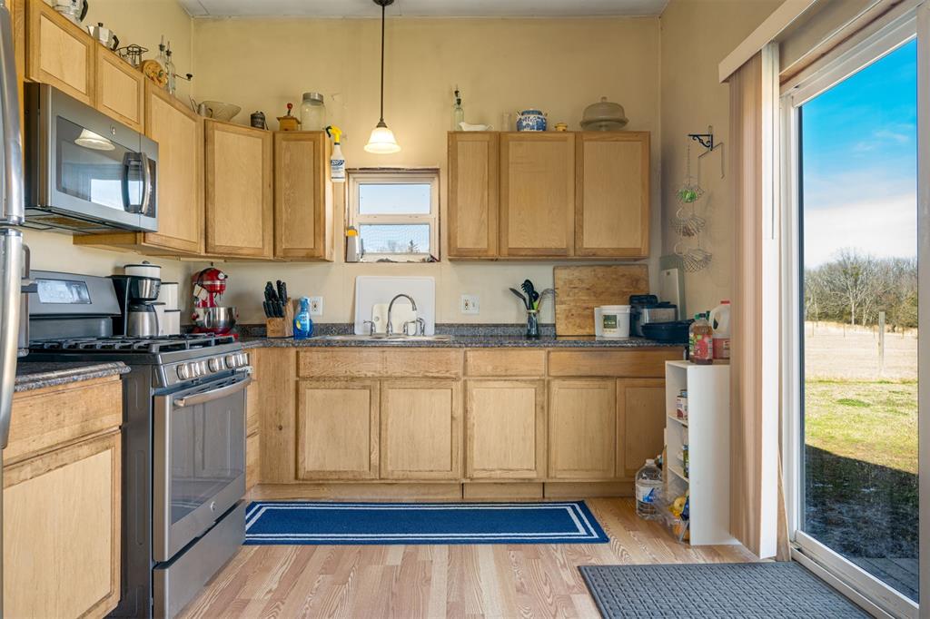 1900 County Road 33900 Powderly, TX 75473 - Photo 25 of 40 a kitchen with stainless steel appliances granite countertop a refrigerator a sink dishwasher and white cabinets with wooden floor