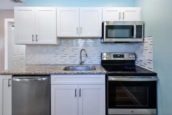 a kitchen with stainless steel appliances granite countertop white cabinets granite counter tops and a hard wood floors