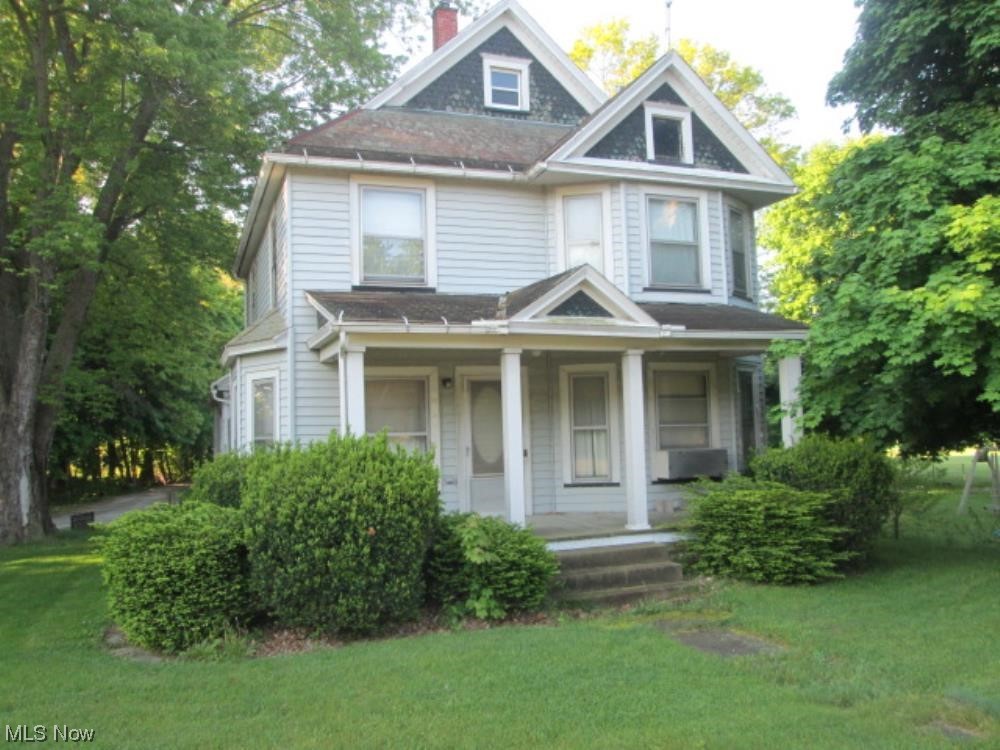Victorian-style house with a porch and a front lawn