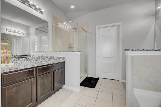 a spacious bathroom with a granite countertop sink a mirror and a bathtub