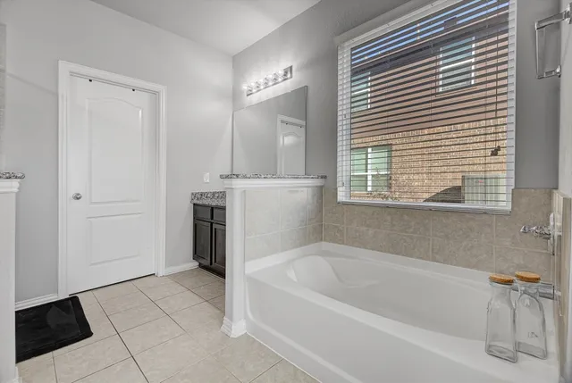 a white bath tub sitting in a en suite bathroom next to a window