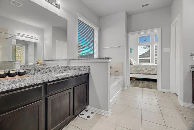 a en suite bathroom with a granite countertop sink and a mirror