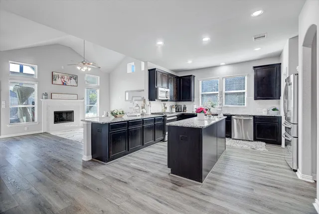 a large kitchen with stainless steel appliances kitchen island granite countertop a stove and a sink