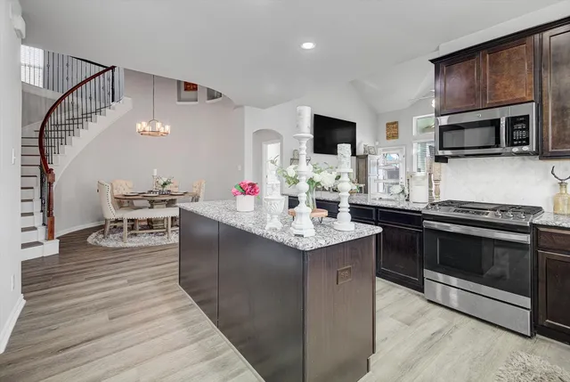 a kitchen with stainless steel appliances granite countertop a kitchen island a stove a sink and a microwave
