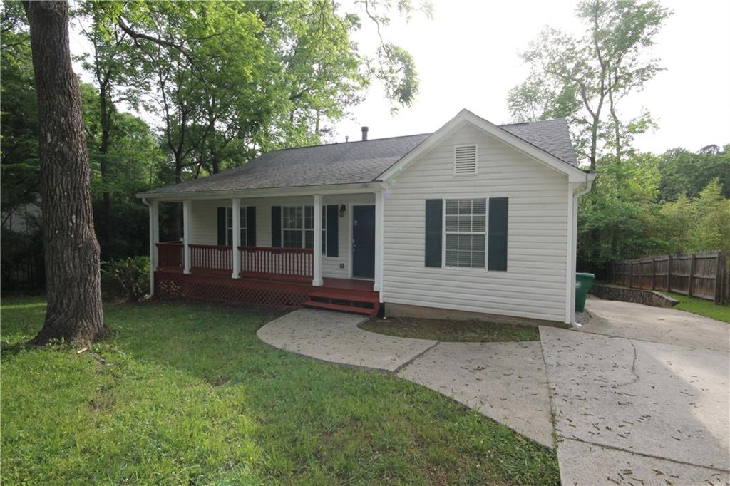 a view of a house with a yard plants and large tree