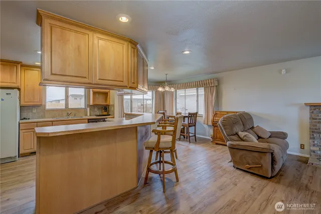 a living room with furniture a dining table wooden floor and kitchen view