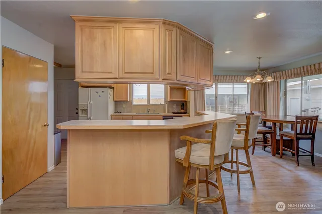 a kitchen with stainless steel appliances granite countertop a table chairs sink and cabinets