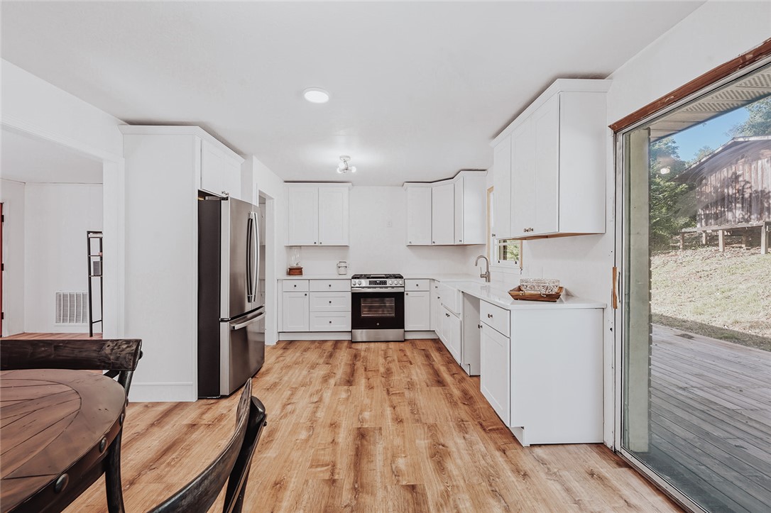 209 Cleveland Pike Road Westminster, SC 29693 - Photo 6 of 30 A well-lit kitchen with sleek white cabinetry and resilient wood flooring awaits.