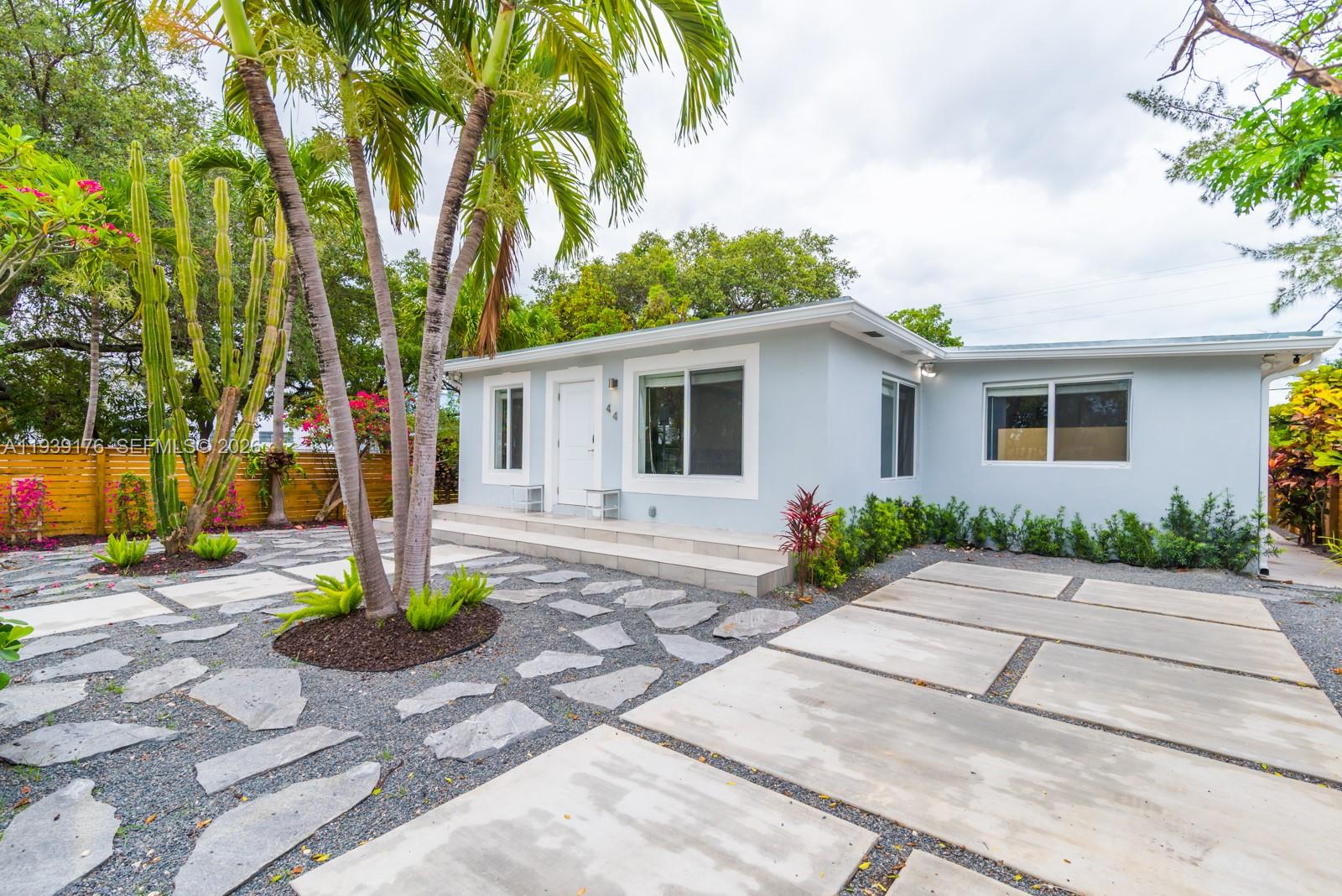 a front view of a house with a yard and potted plants