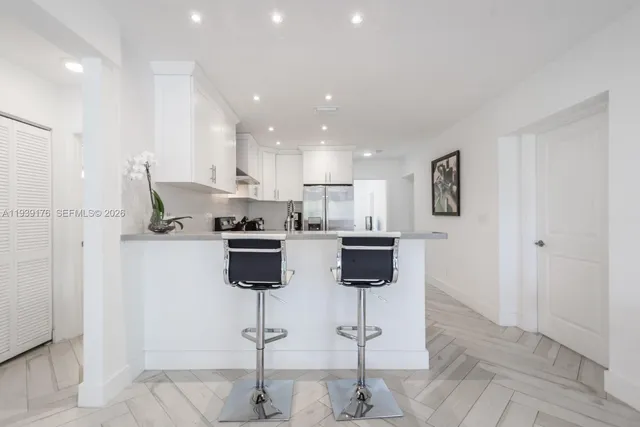 a kitchen with stainless steel appliances kitchen island sink refrigerator and cabinets
