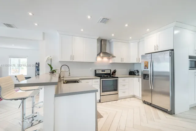 a kitchen with stainless steel appliances granite countertop a sink stove refrigerator and cabinets