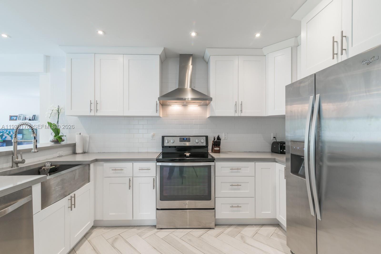 44 Northwest 40th Street Miami, FL 33127 - Photo 10 of 25 a kitchen with white cabinets and stainless steel appliances