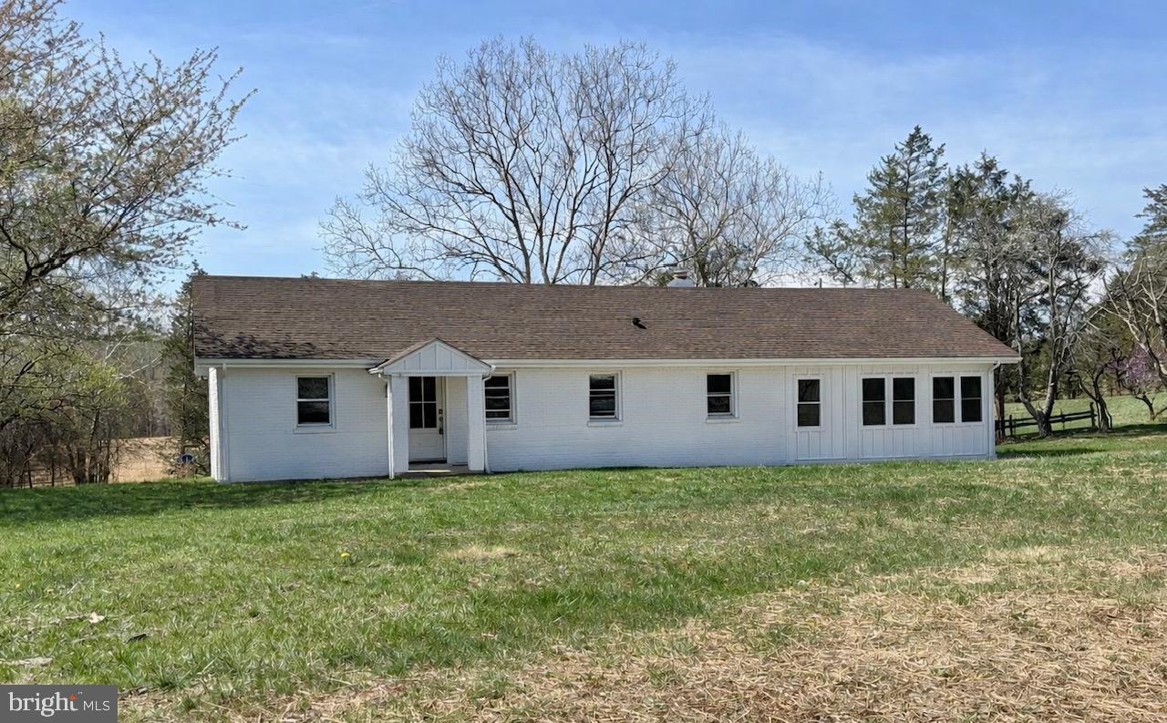 a house that is sitting in the grass with tress in the yard