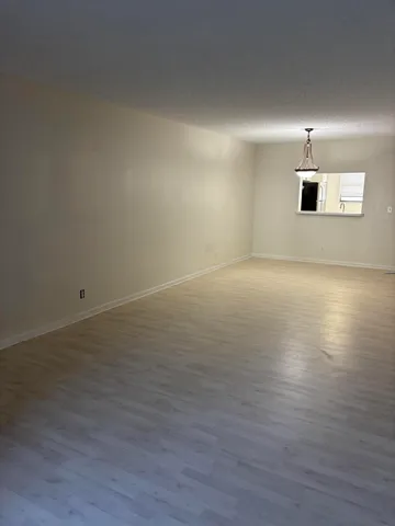 a room with a chandelier fan and wooden floor