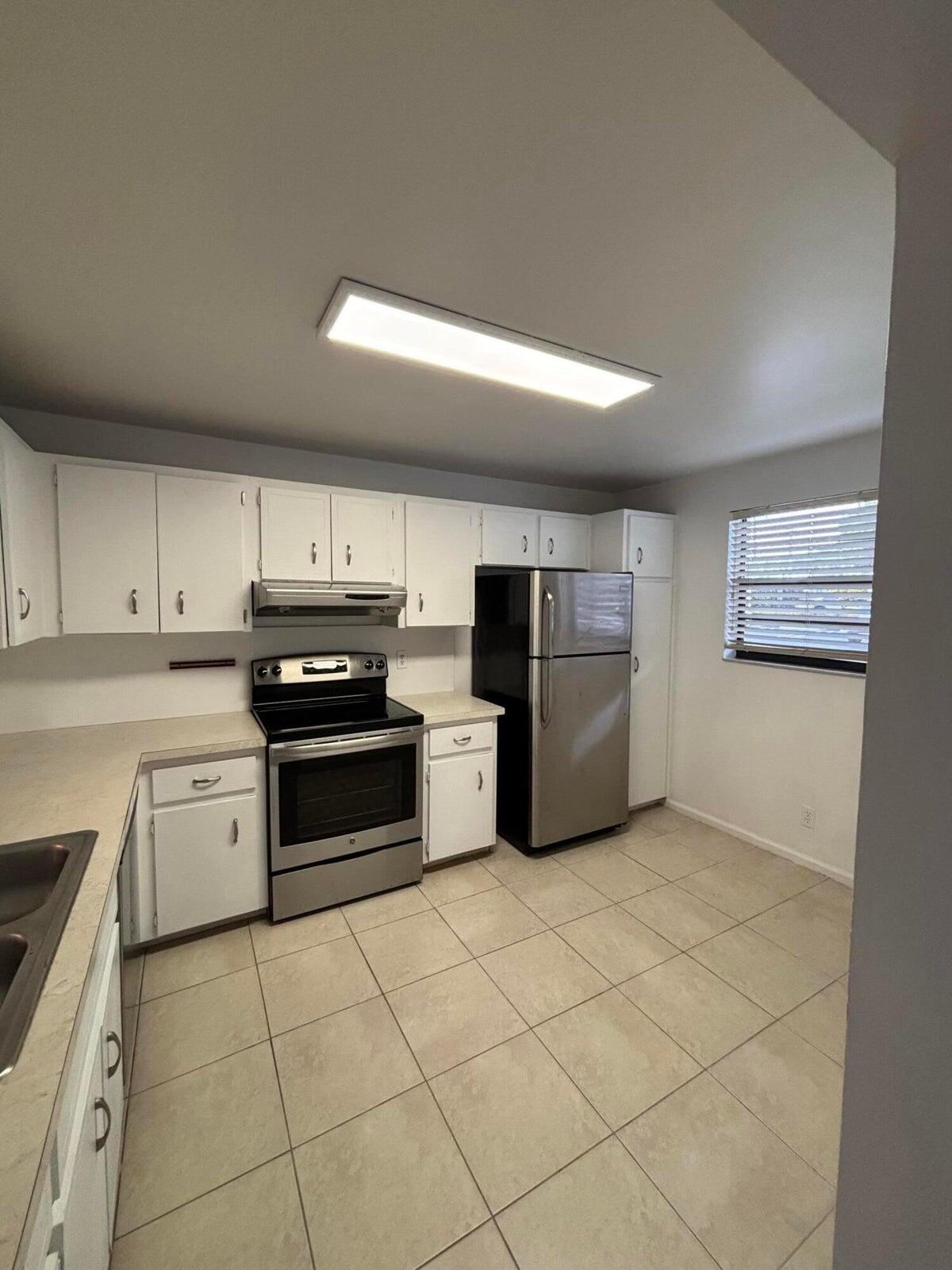 555 Banyan Tree Lane, Unit 109 Delray Beach, FL 33483 - Photo 2 of 17 a kitchen with granite countertop a refrigerator and a stove top oven