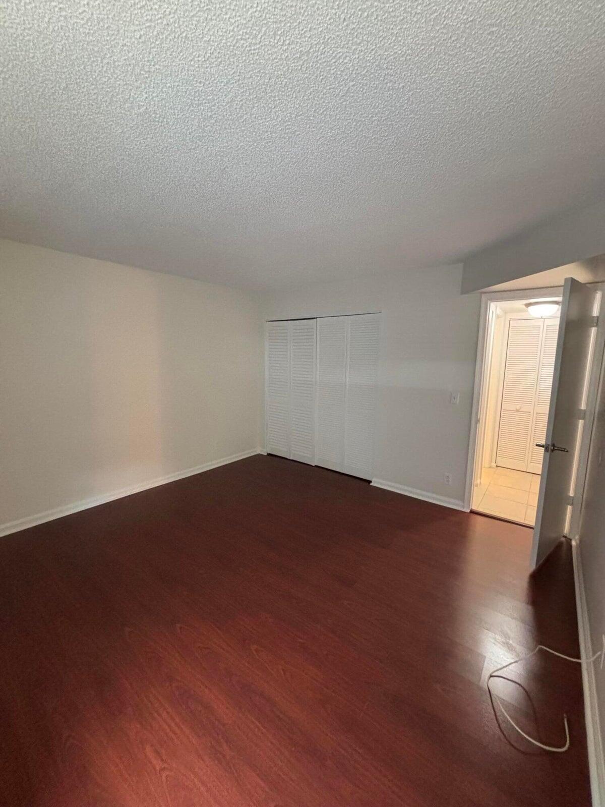 555 Banyan Tree Lane, Unit 109 Delray Beach, FL 33483 - Photo 5 of 17 an empty room with wooden floor and windows