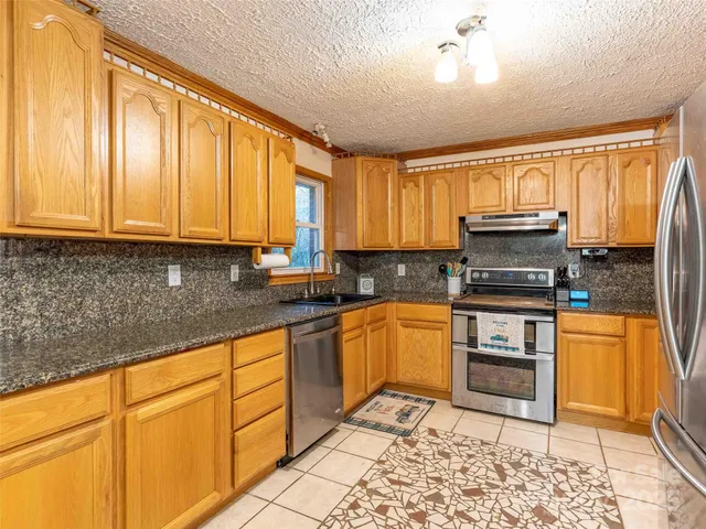 a kitchen with stainless steel appliances granite countertop a stove a sink and a microwave