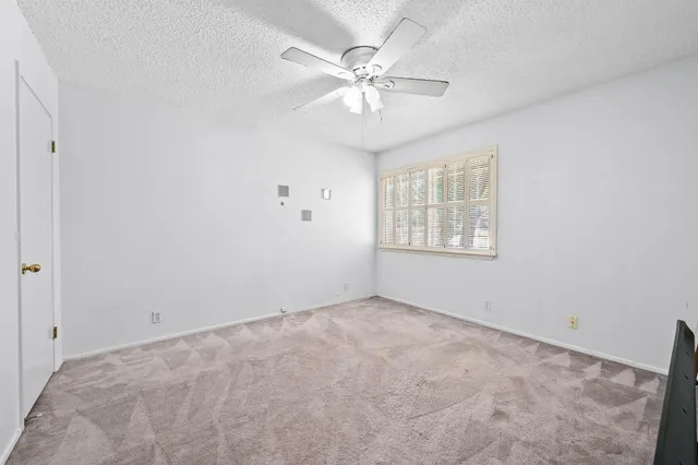 an empty room with chandelier fan and windows