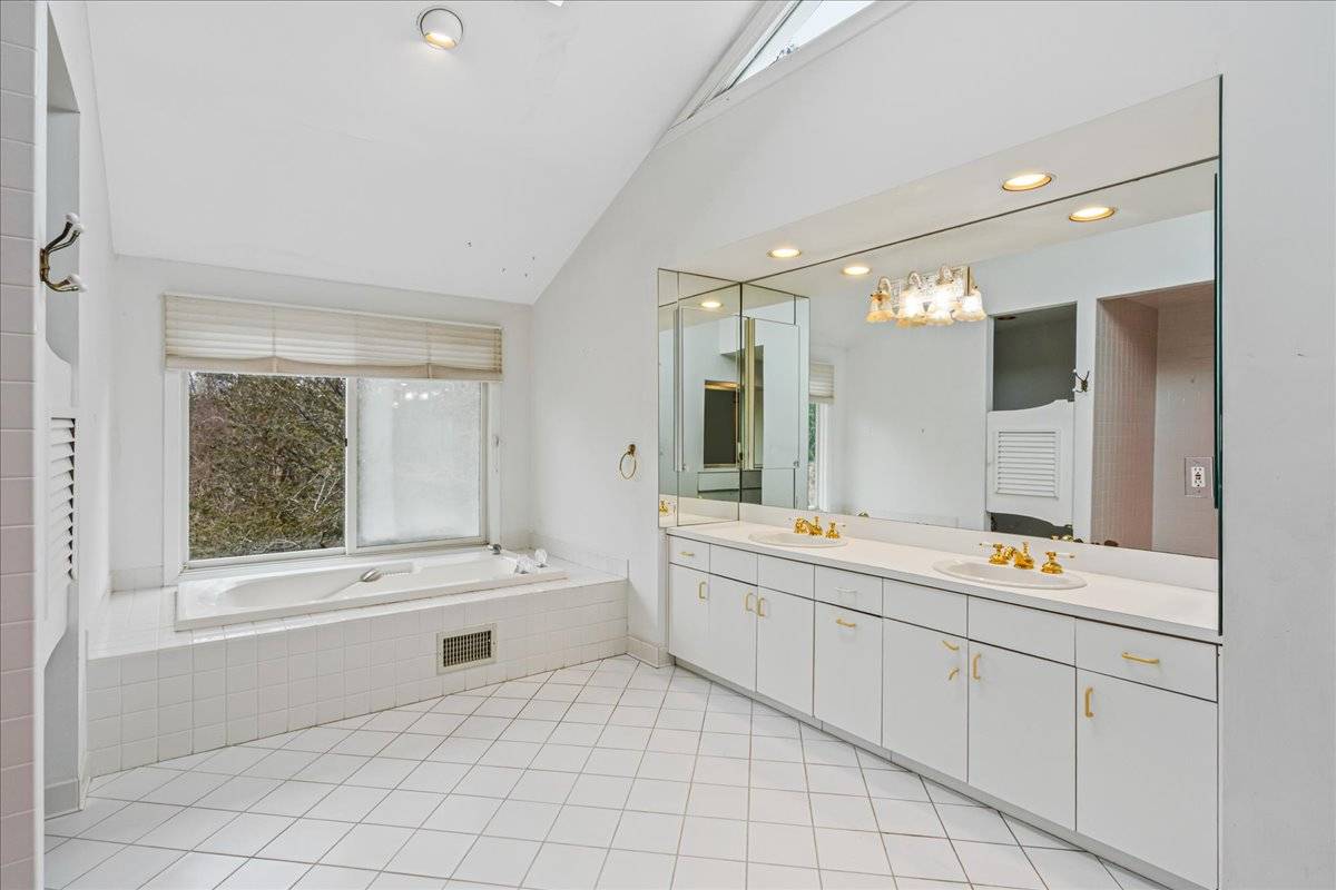 8 Fiddler Crab Trail Westhampton, NY 11977 - Photo 36 of 43 a bathroom with a sink mirror and a bathtub next to a window