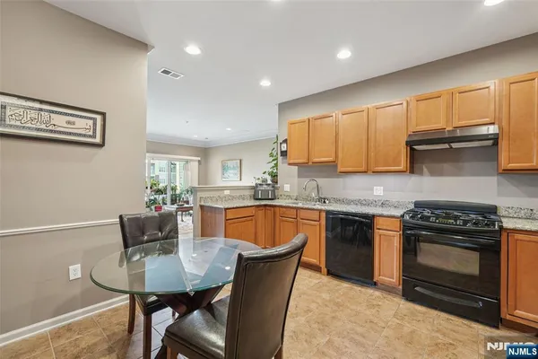 a kitchen with stainless steel appliances granite countertop a stove a sink a microwave a dining table and chairs
