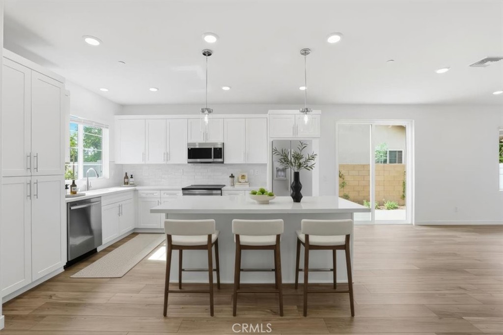 413 East 220th Street Carson, CA 90745 - Photo 6 of 15 a kitchen with stainless steel appliances granite countertop a table chairs sink refrigerator and microwave