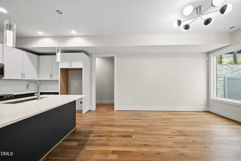 a large kitchen with stainless steel appliances a large counter top a sink a refrigerator and a window