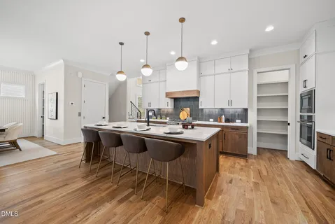 a kitchen with kitchen island a sink a stove a dining table and chairs