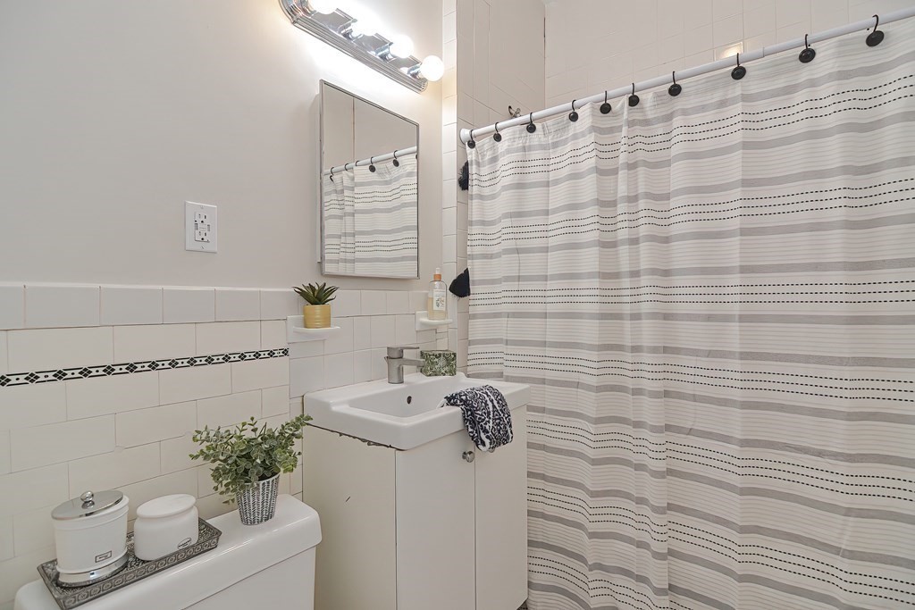 87 Broad Street, Unit 2 Lynn, MA 01902 - Photo 23 of 28 a bathroom with a sink a toilet and shower curtain