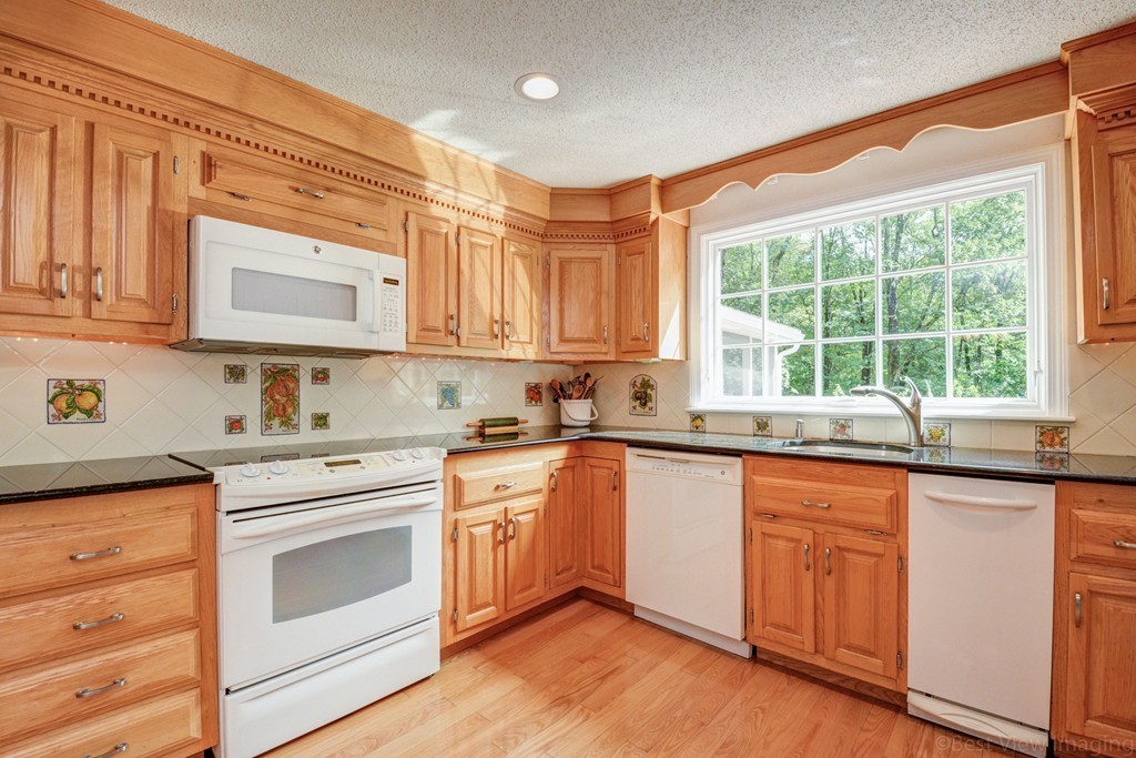 351 Liberty Square Road Boxborough, MA 01719 - Photo 4 of 30 a kitchen with granite countertop wooden cabinets and white appliances