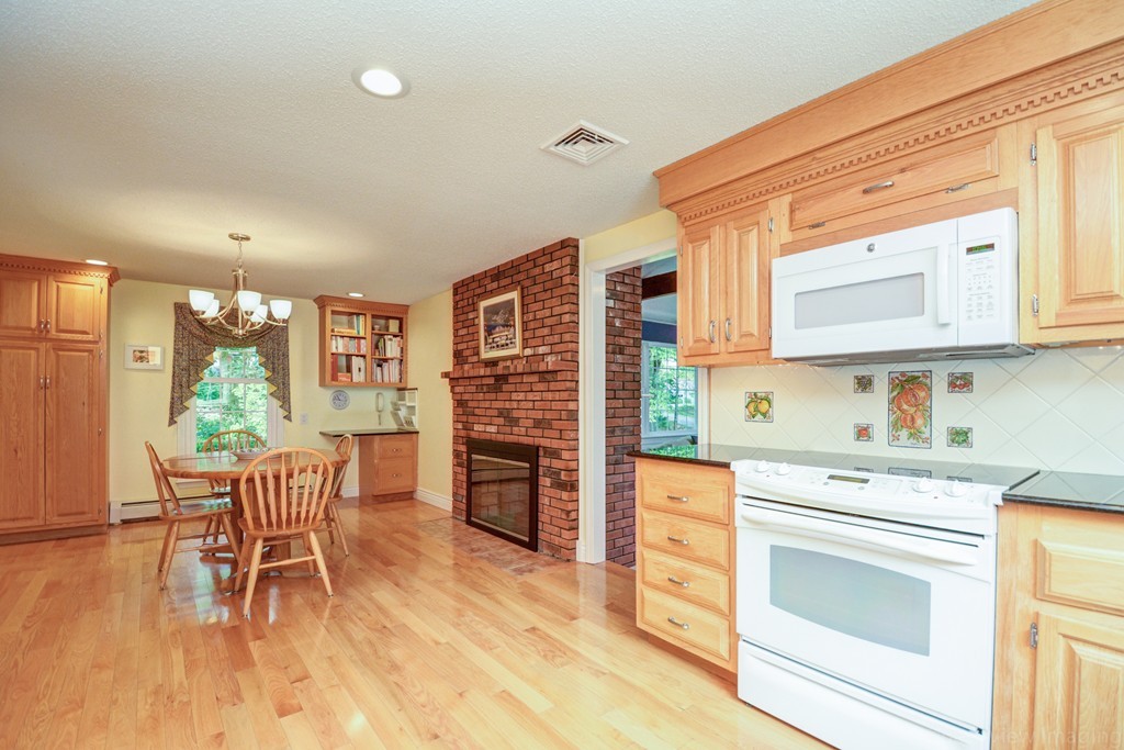 351 Liberty Square Road Boxborough, MA 01719 - Photo 7 of 30 a kitchen with stainless steel appliances granite countertop a stove top oven a dining table and chairs with wooden floor