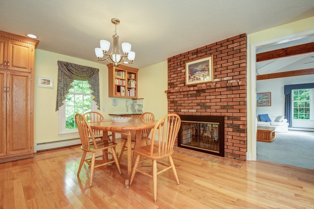 351 Liberty Square Road Boxborough, MA 01719 - Photo 8 of 30 a dining room with furniture a fireplace and wooden floor