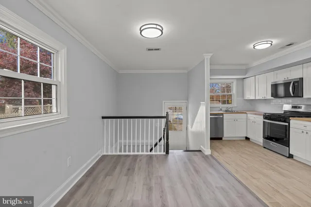 a kitchen with cabinets wooden floor and stainless steel appliances