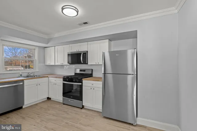 a kitchen with stainless steel appliances granite countertop a refrigerator a stove a sink and a microwave