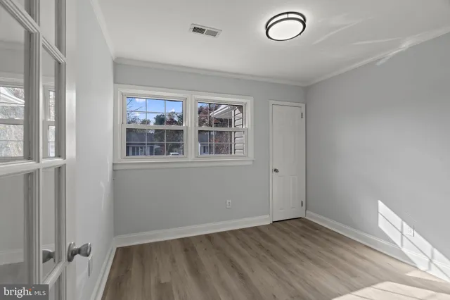 an empty room with wooden floor and windows
