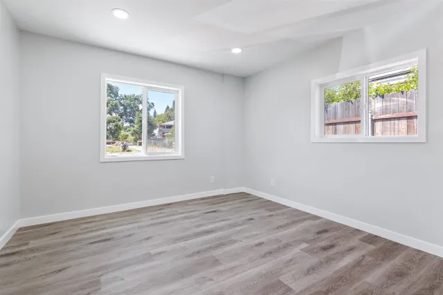 a view of an empty room with wooden floor and window