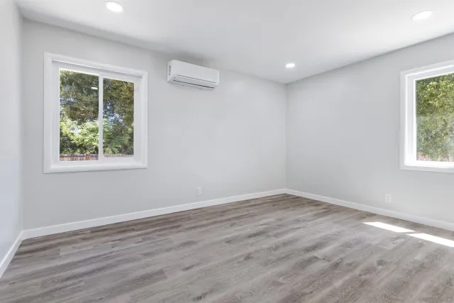 an empty room with wooden floor and windows