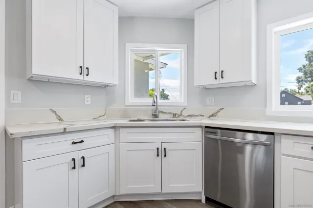 a kitchen with white cabinets and a window