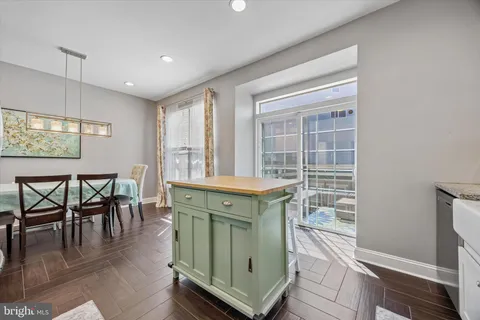 a kitchen with granite countertop a stove a dining table and chairs with wooden floor