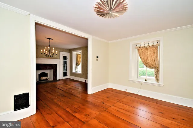 a view of an empty room with a window and wooden floor