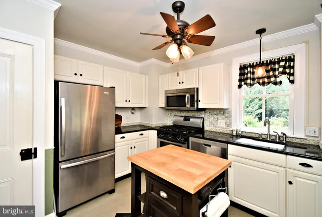 a kitchen with stainless steel appliances a stove a refrigerator a sink and white cabinets