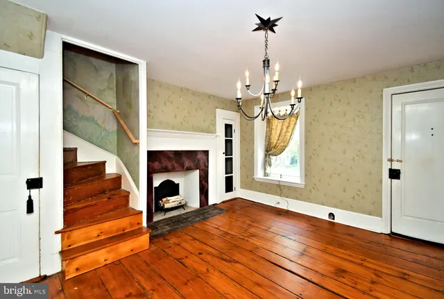 a view of a livingroom with wooden floor a fireplace and window