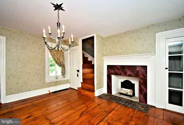 a view of empty room with wooden floor fireplace and window