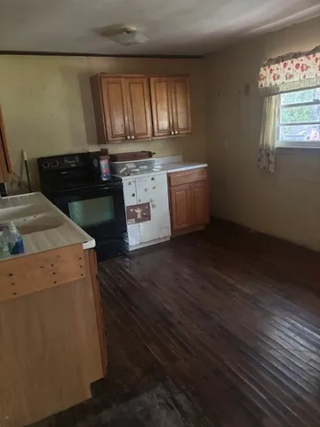 a kitchen with granite countertop wooden cabinets and a wooden floor